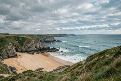 Vue panoramique d'un littoral breton sauvage avec falaises de granit, plages dorées et eaux turquoise de l'Atlantique
