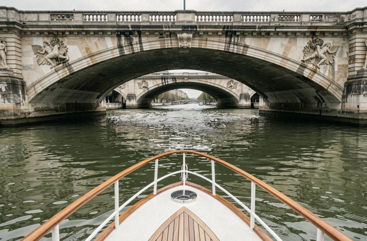 Vue depuis le pont d'un bateau de croisière passant sous un pont historique sur la Seine à Paris